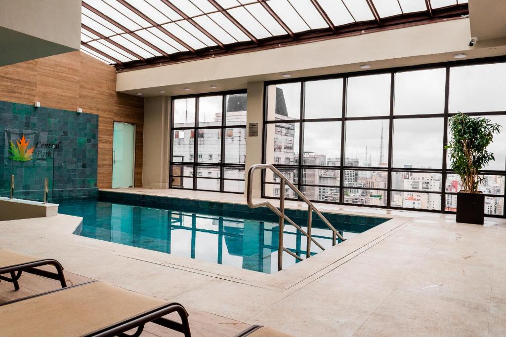 a swimming pool in a building with windows at Central Park Flat Jardins in Sao Paulo