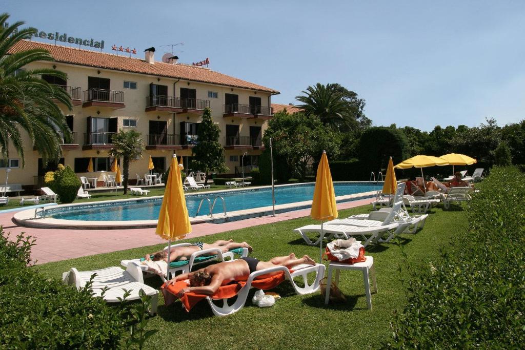 a group of people laying on lawn chairs next to a pool at Arcada Hotel in Tocha