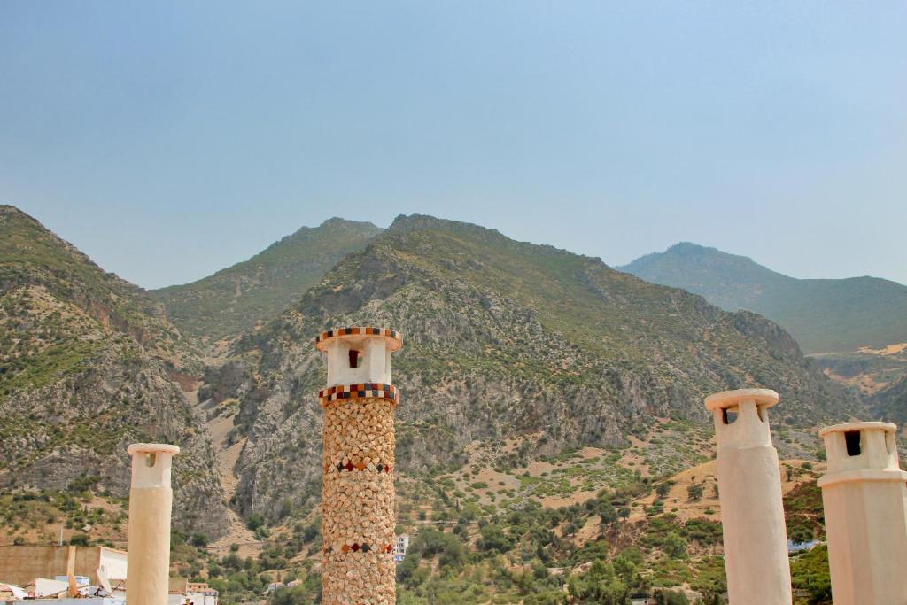 a group of three towers with mountains in the background at RIAD LA SANTA in Chefchaouen