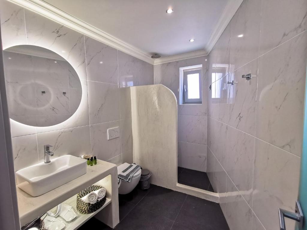 y baño blanco con lavabo y ducha. en Noir Santorini, en Monolithos