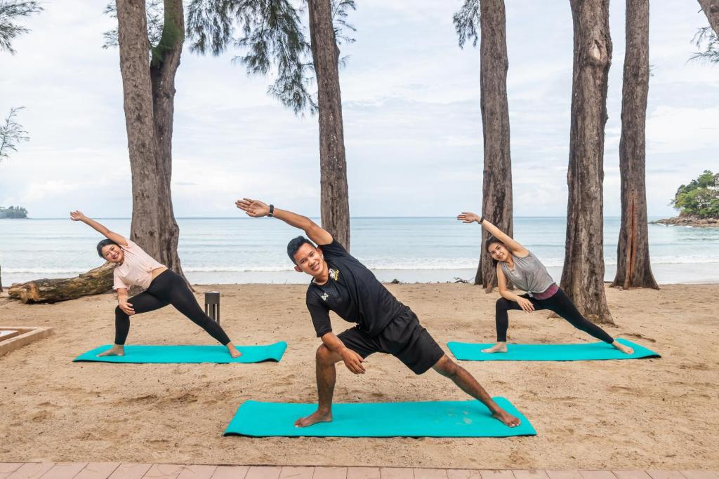 a group of people doing yoga on the beach at InterContinental Phuket Resort by IHG in Kamala Beach