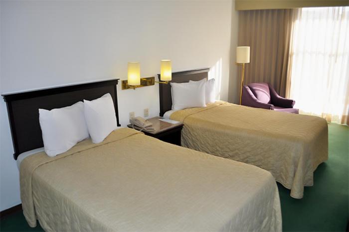 una habitación de hotel con 2 camas y una silla en Arroyo Express, en Zacatecas