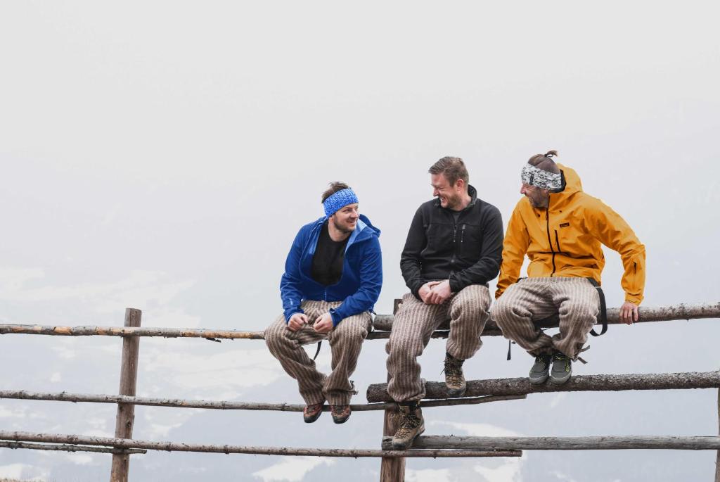 a group of three men sitting on top of a fence at Hotel Wochtla Buam in Brunico