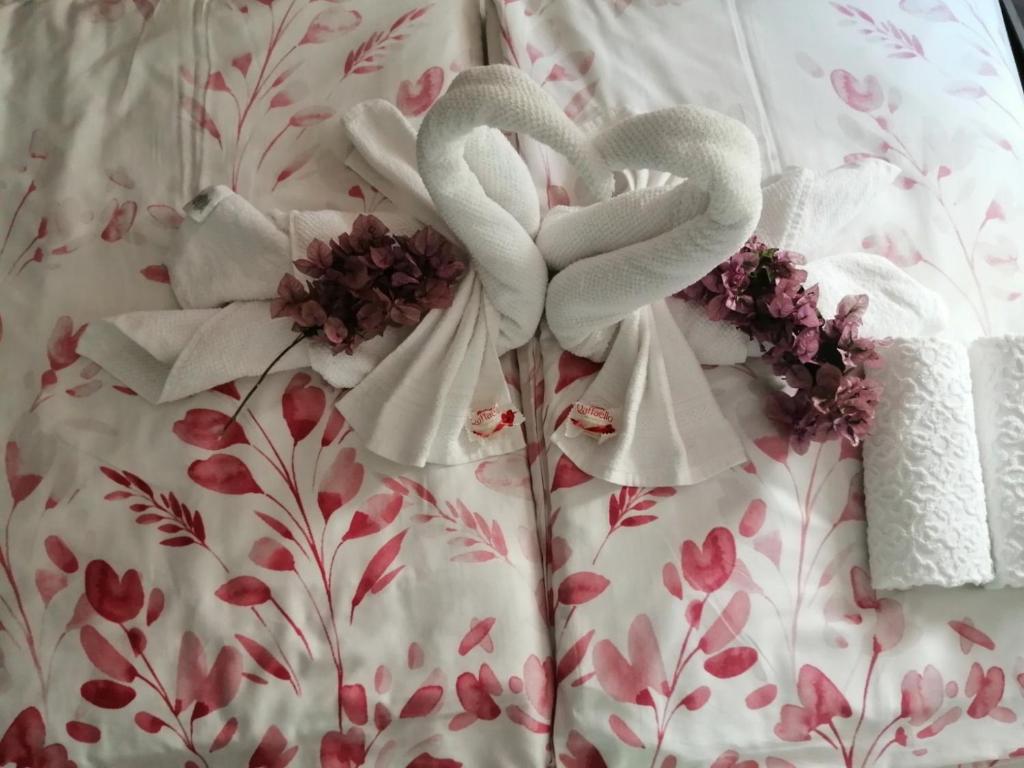 two white swans on a bed with flowers at Sun & Love Apartment in Koper