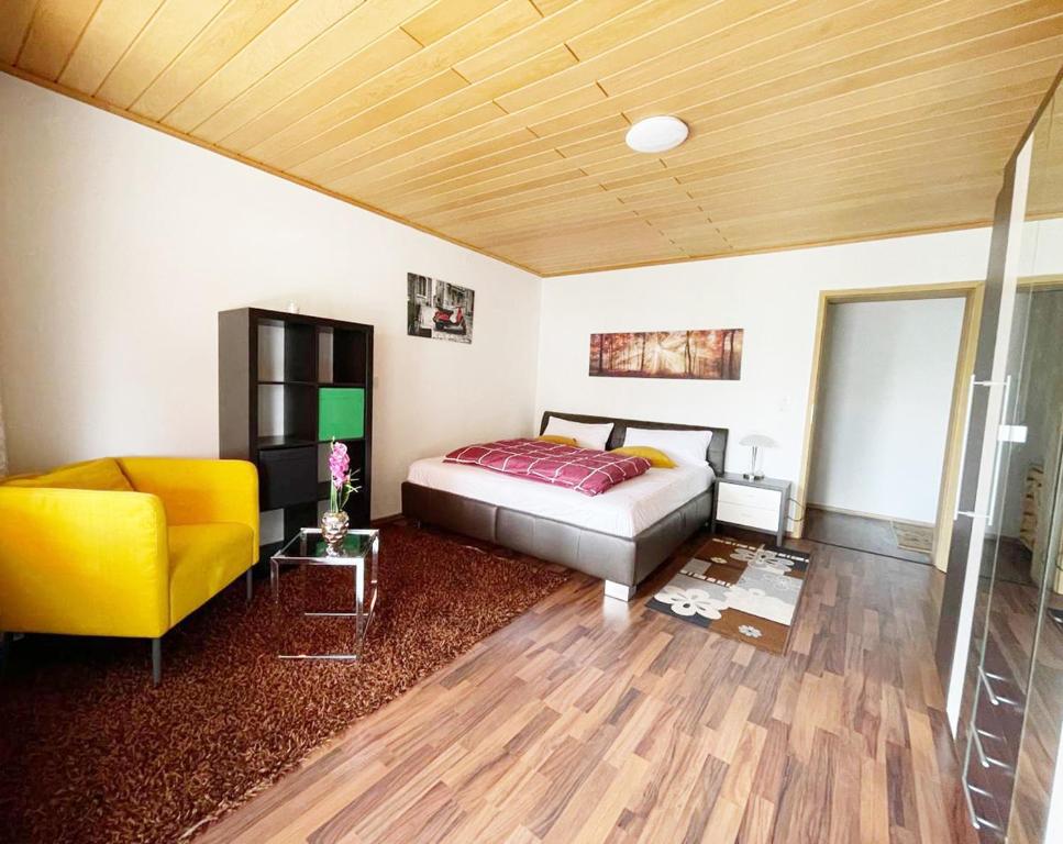 a bedroom with a bed and a yellow chair at FeWo Royal & Goodness Home in Mühlhausen