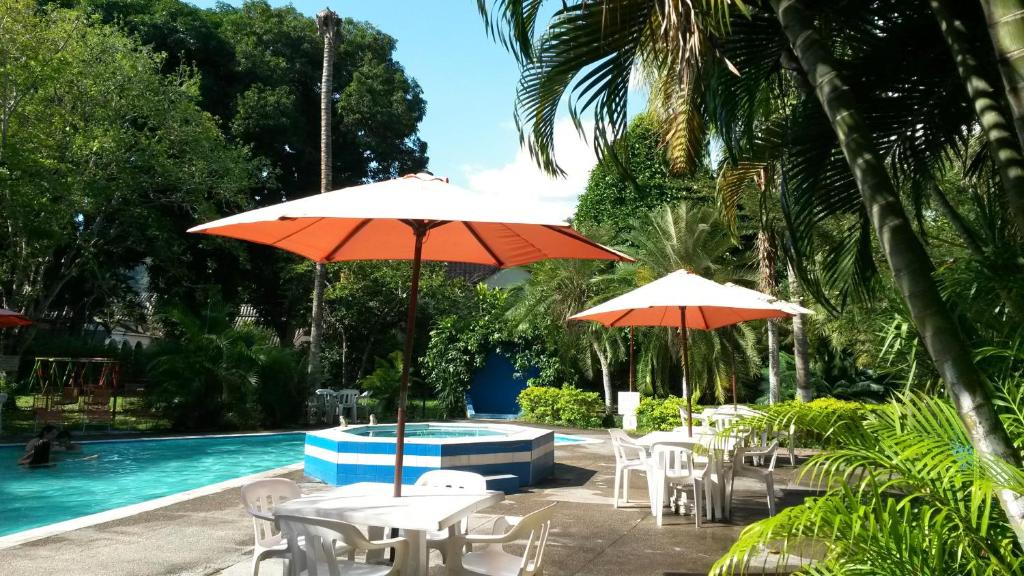a group of tables and umbrellas next to a swimming pool at VILLA GLADHYS CASA CAMPESTRE in Honda