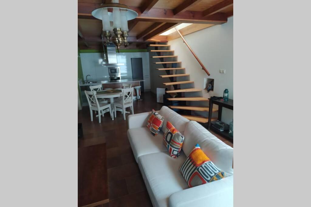 a living room with a white couch and a staircase at Casa de piedra acogedora a 2 minutos de la playa in Laxe