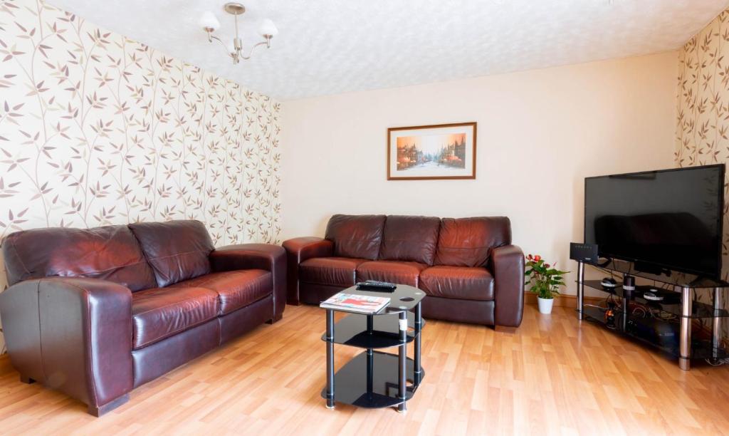ein Wohnzimmer mit 2 Ledersofas und einem Flachbild-TV in der Unterkunft Room near to Birmingham city centre with parking in Birmingham