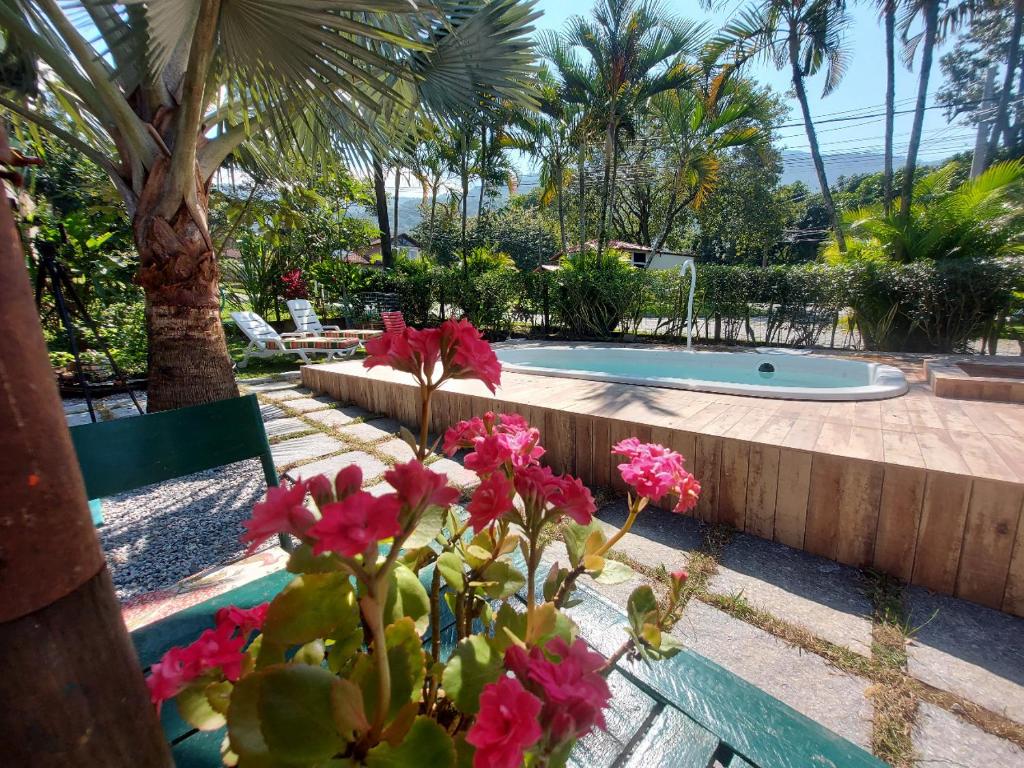 a garden with a swimming pool and pink flowers at Eco Paradise Muriqui in Mangaratiba