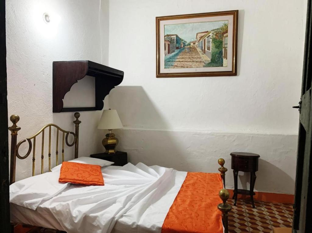 a bedroom with a bed with an orange blanket on it at Casa Museo Alcantus in Puente Nacional