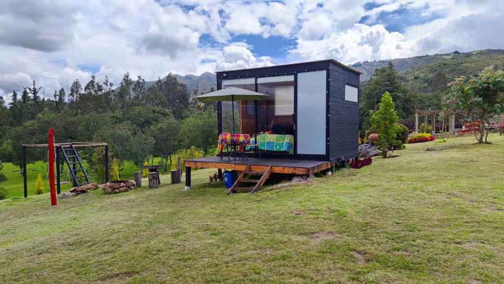 a black tiny house sitting on top of a field at Iraca Glamping in Guatavita