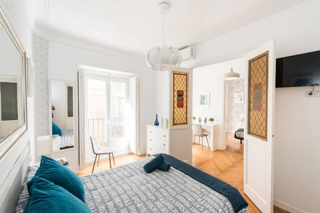 a white bedroom with a bed and a living room at Apartamentos Coloreros, SOL, Madrid Centro in Madrid