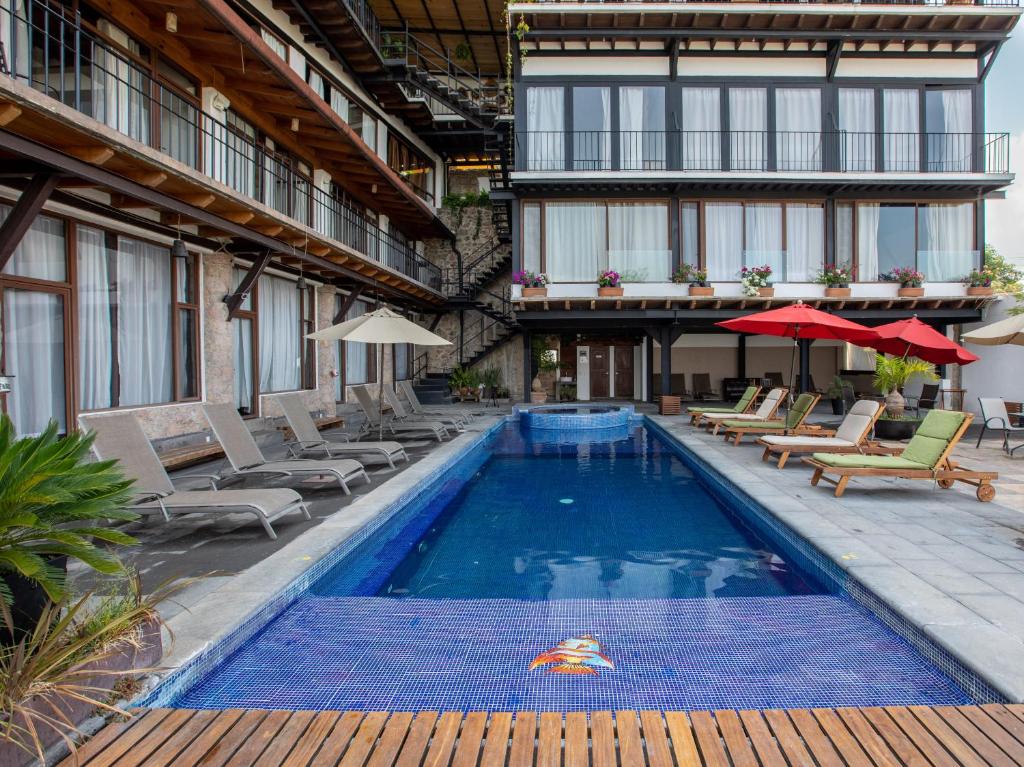 uma piscina com cadeiras e guarda-sóis ao lado de um edifício em Hotel Santa Rosa em Valle de Bravo