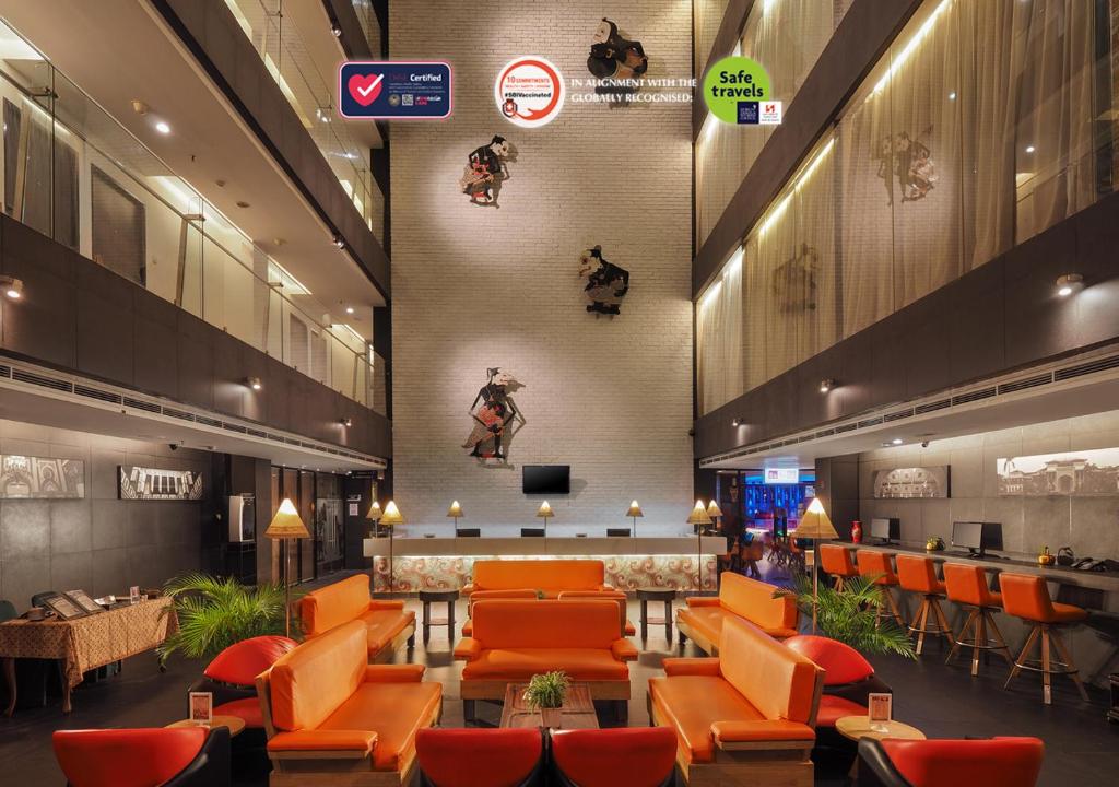 a hotel lobby with orange chairs and a bar at Swiss-Belinn Medan in Medan