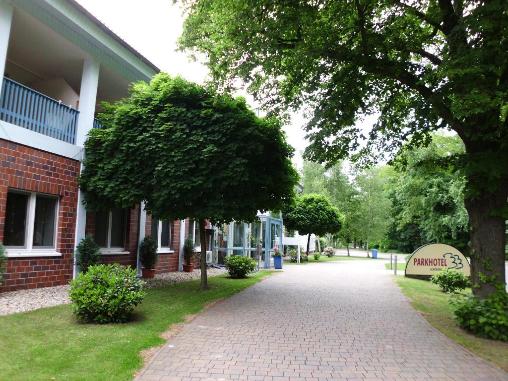 a brick building with a tree next to a sidewalk at Parkhotel Schönewalde in Schönewalde