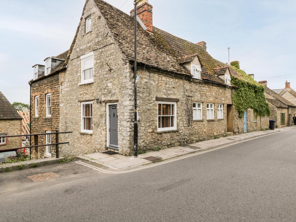 an old stone house on the side of a street at Corner Cottage in Malmesbury