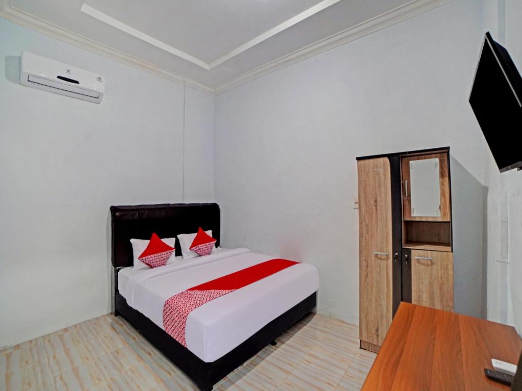 a bedroom with a bed and a television and a table at OYO 90503 Madina Residence Syariah in Medan