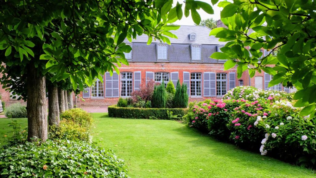 a house with a garden of flowers and bushes at Château d'Aigneville in Aigneville