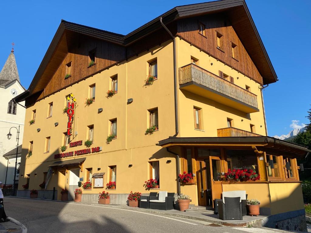 a large yellow building with a brown roof at Hotel Trieste in Tarvisio