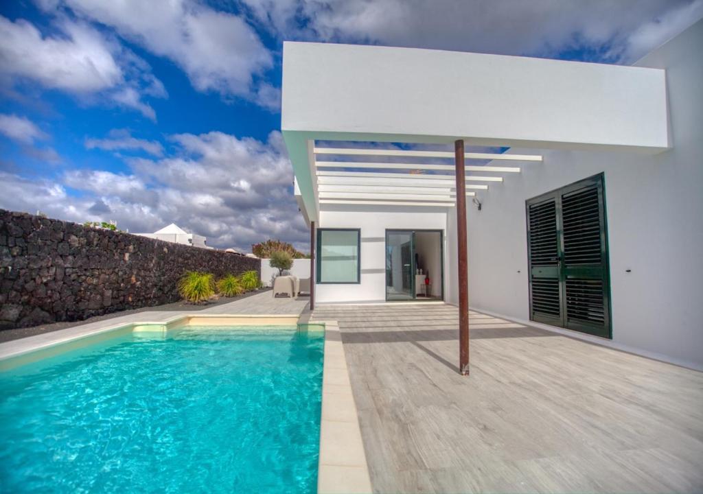 a villa with a swimming pool in front of a house at Lava Dreams in Yaiza