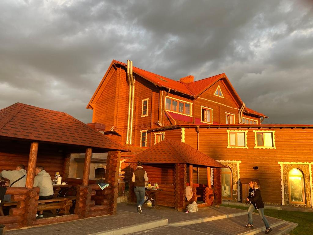 una gran casa de madera con gente caminando delante de ella en Panorama Karpat, en Yablunytsya