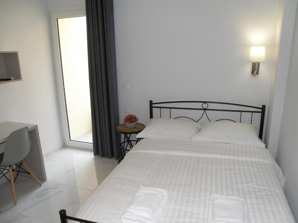 a bedroom with a bed with white sheets and a window at Talos apartments and studios in Heraklio Town