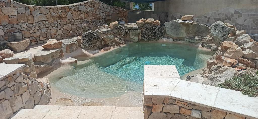 una gran piscina de agua con una pared de piedra en Villa Cà del Mar, en Morciano di Leuca