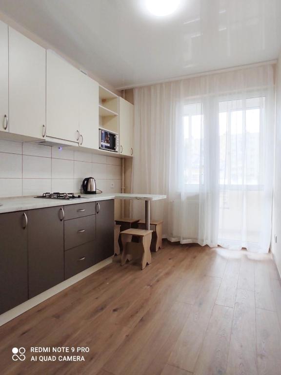 cocina con armarios blancos y suelo de madera en Елітна квартира в новобудові, en Leópolis
