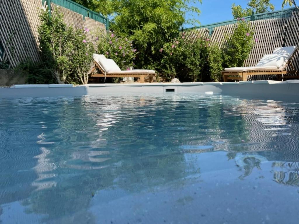 a swimming pool with blue water in a yard at Maison d'hôtes Aux Deux Cigognes in Gries