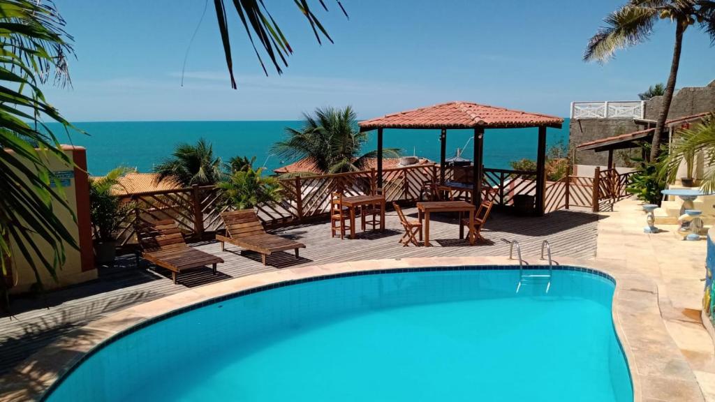 uma piscina com mesa e cadeiras e o oceano em Pousada Nova Oasis do Rei em Canoa Quebrada