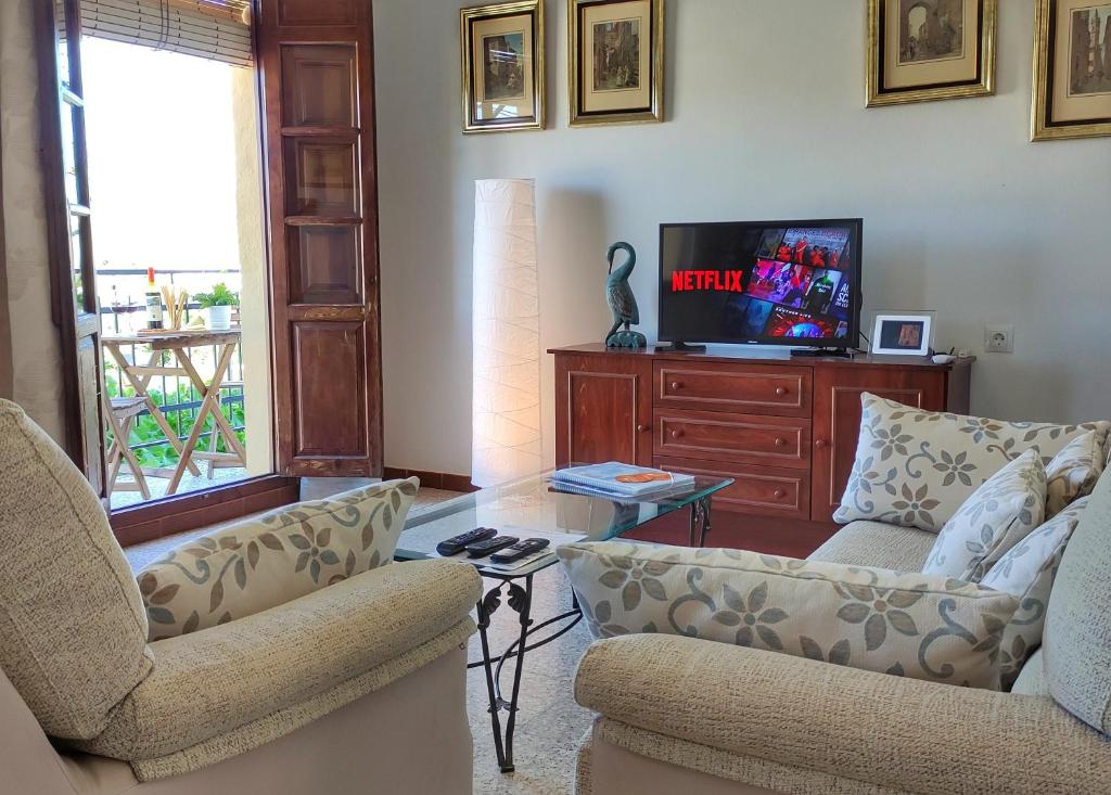 a living room with two chairs and a tv at El Rancho Grande - Apartamento in Alora