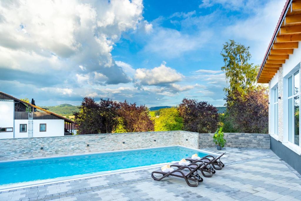 a swimming pool with chairs next to a house at Hotel Rhön Residence in Dipperz