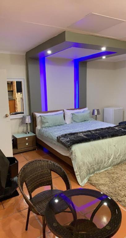 1 dormitorio con cama, silla y luces púrpuras en Made Guest House, en Sandton