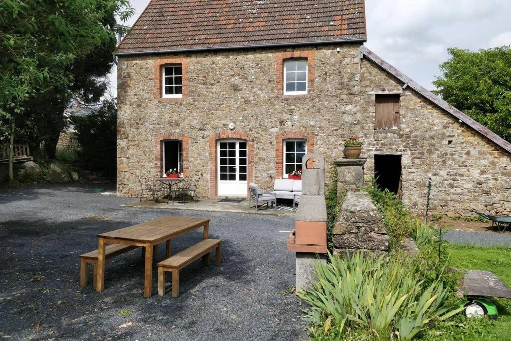 a brick building with a table and a bench in front of it at Le Portail Du Mont in Montpinchon