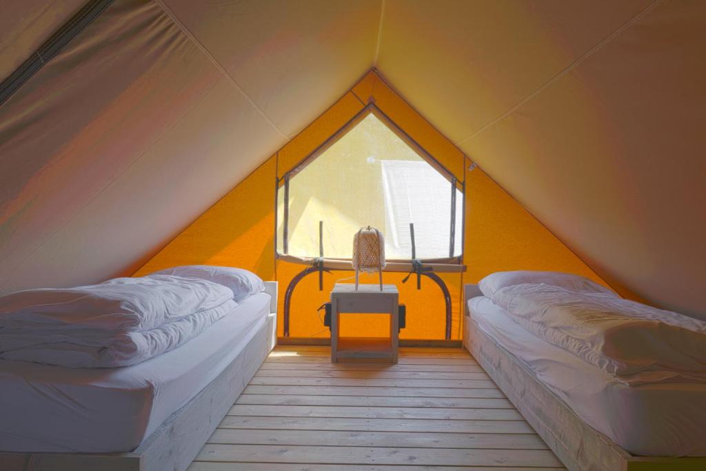 a room with two beds and a window in a tent at Nomad Knokke in Knokke-Heist