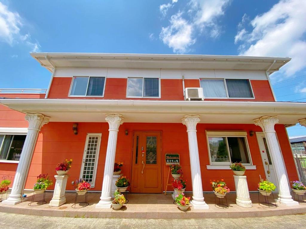 una casa naranja con columnas blancas y una puerta roja en Golf house - Vacation STAY 9043 en Ryūgasaki
