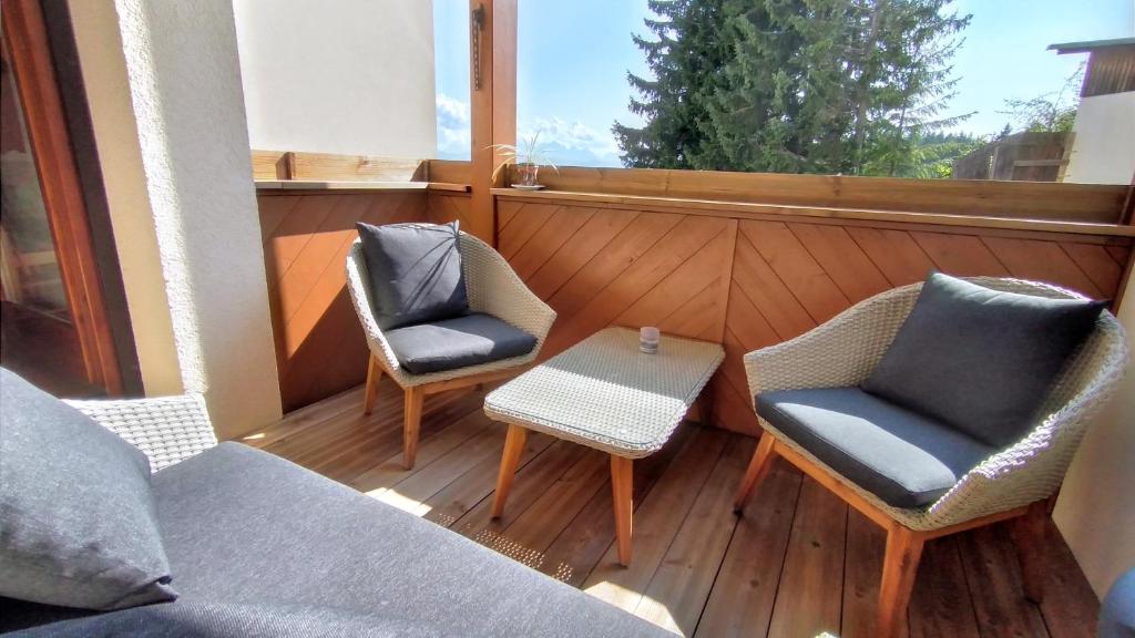 balcón con sillas, mesa y sofá en GOOD Times Gerlitzen, en Deutschberg