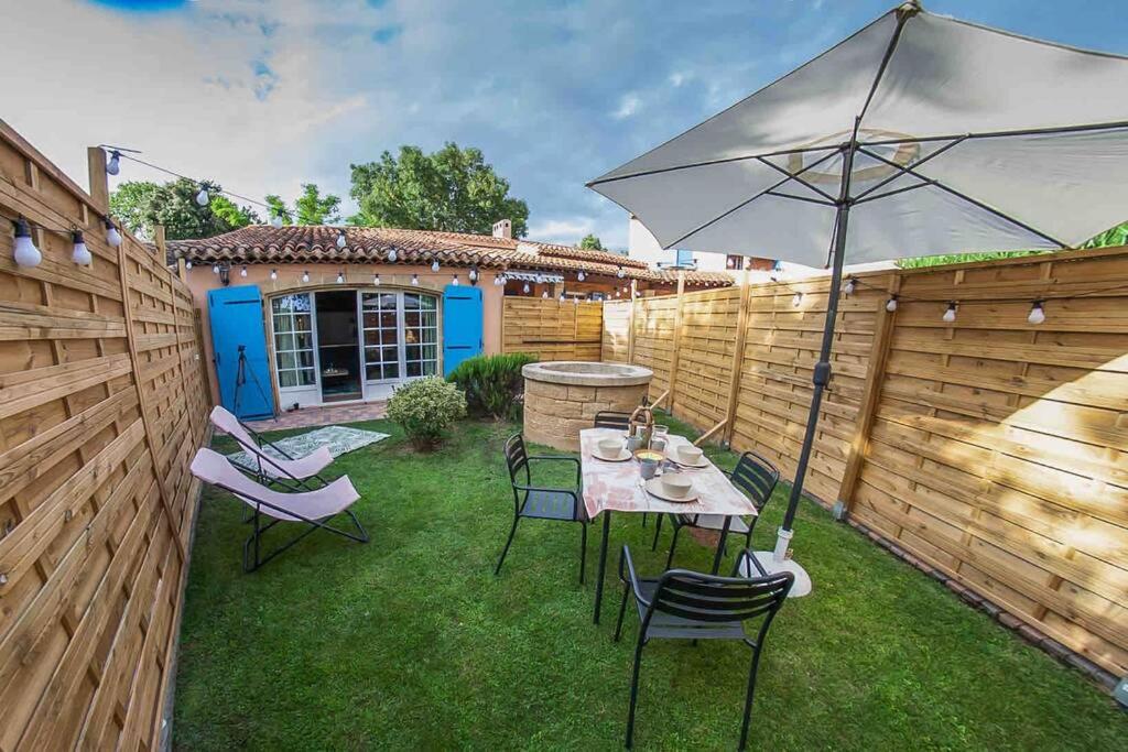 eine Terrasse mit einem Tisch und Stühlen mit einem Sonnenschirm in der Unterkunft Charmant studio/T2 au calme avec jardin et parking in Fos-sur-Mer