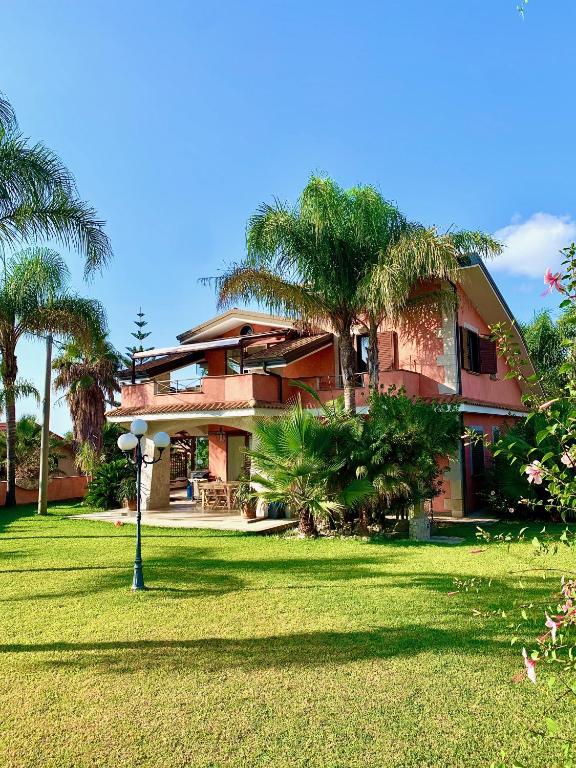 a house with palm trees in front of it at Villa Maris Capo Vaticano in Capo Vaticano
