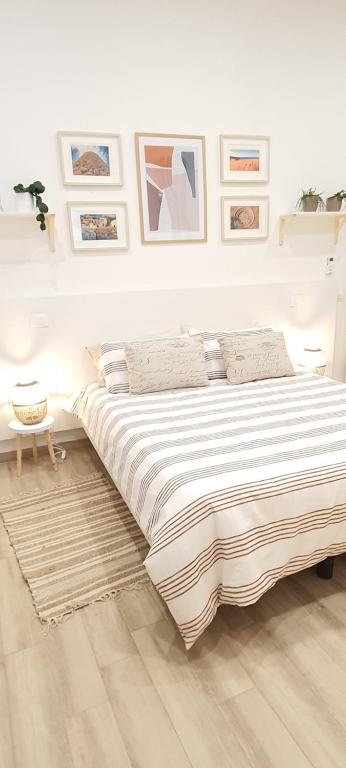 a white bedroom with a large bed and pictures on the wall at SUITE BLANC APARTMENTS - Monolocali indipendenti con cucina e bagno privato - Check-in e check-out con codice in autonomia h24 - Terrazza in comune in Guspini