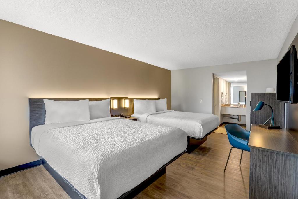 Cette chambre comprend deux lits et une télévision. dans l'établissement Motel 6 Brooks AB, à Brooks