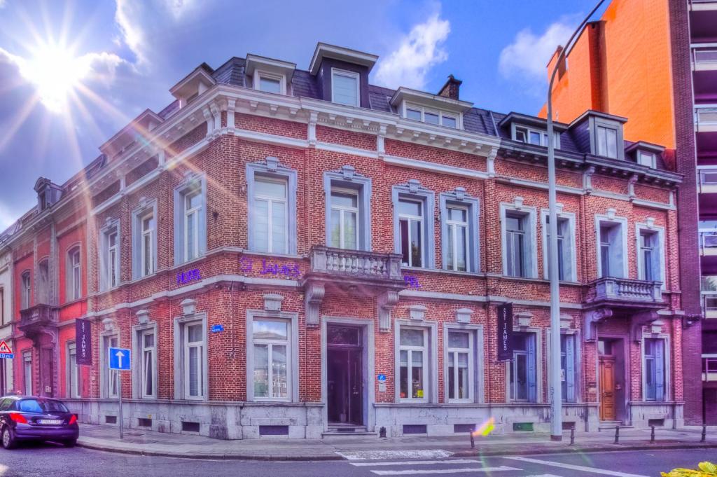 un bâtiment en briques rouges au coin d'une rue dans l'établissement Hotel St James, à Mons