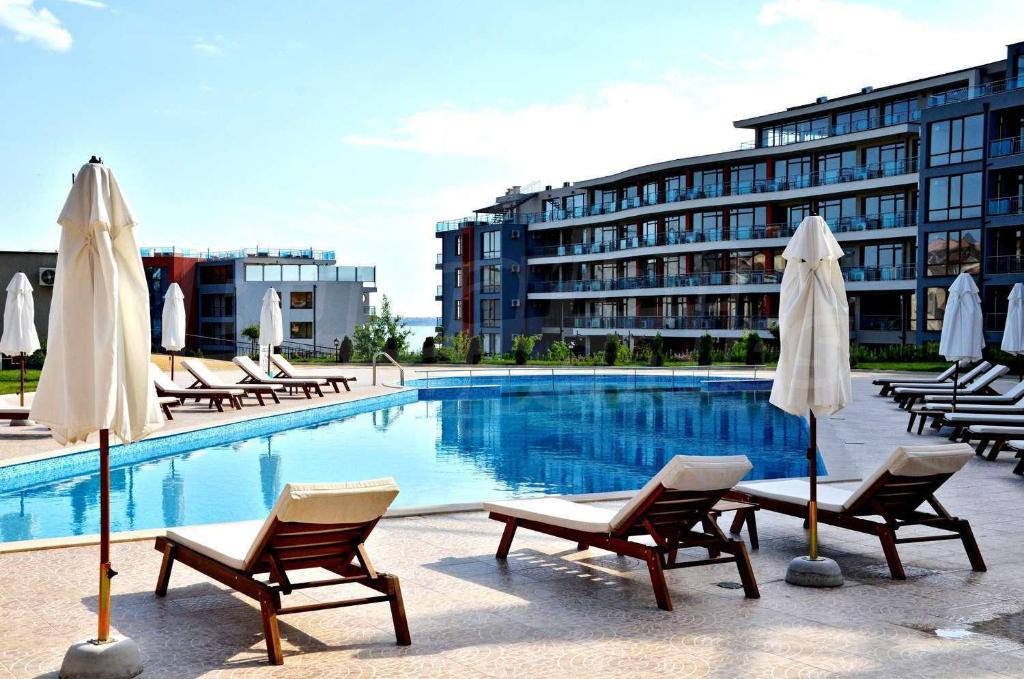 Una piscina con sillas y sombrillas al lado de un edificio. en Apartament in sun waves, en Burgas