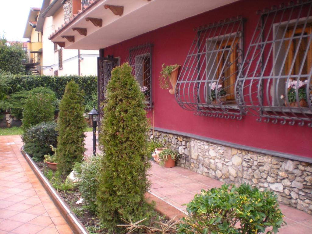 a red house with trees in front of a building at Il Toscano - near Grotta Giusti in Monsummano Terme