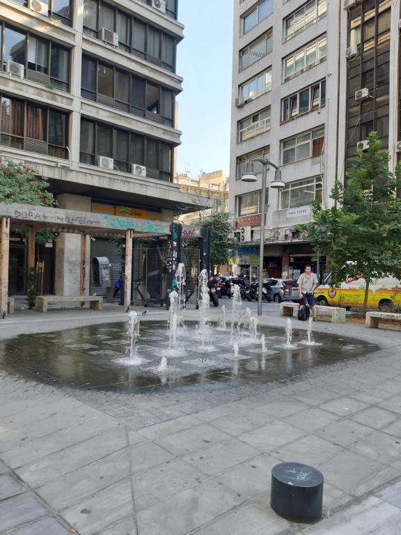 una fontana nel mezzo di una città con edifici di Thessaloniki Center Studio a Salonicco