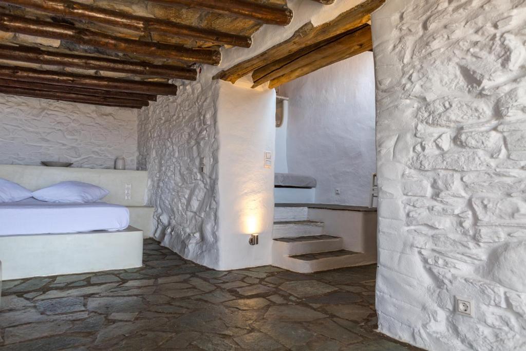 ein Schlafzimmer mit einem Bett und einer Steinmauer in der Unterkunft Spiti Anita, Superior Master & Double Room - Pristine, Serene, Beautiful Views in Gavrio