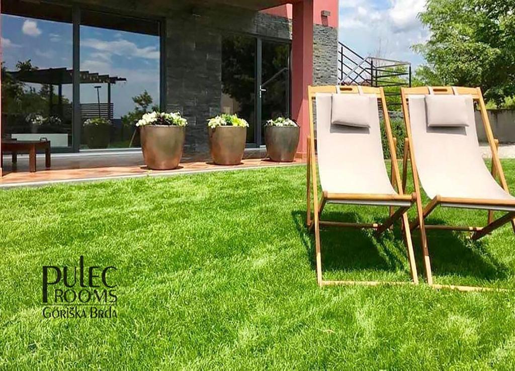 zwei Stühle im Gras vor einem Haus in der Unterkunft Apartma Sobe Pulec in Dobrovo