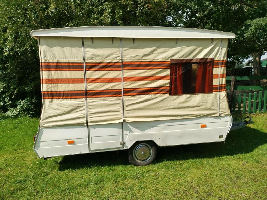 a white trailer with a tent on top of it at Retro Vouwwagen in Tynaarlo