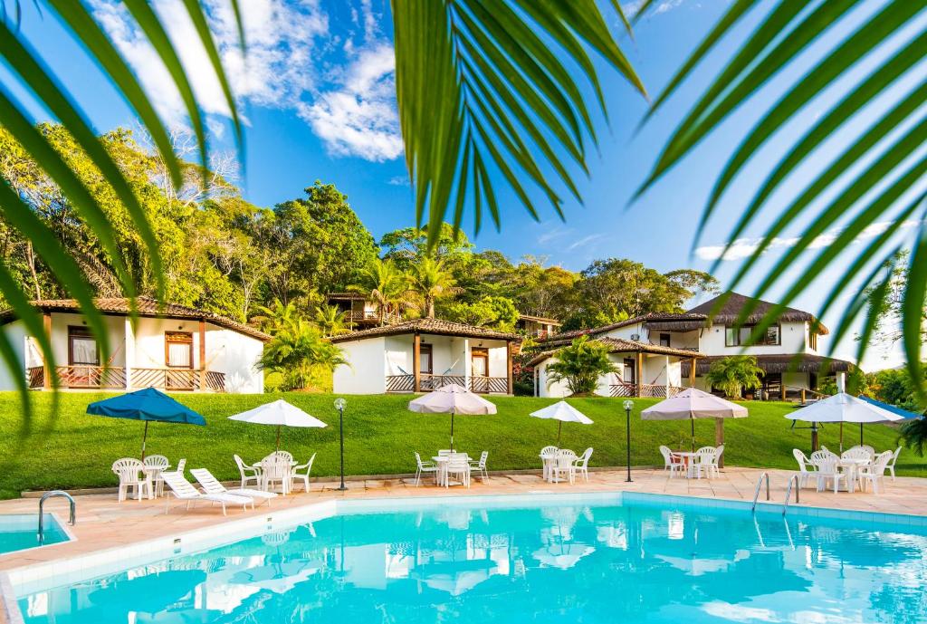 a pool with chairs and umbrellas in front of a house at Hotel Vale do Jiquiriçá in Jiquiriçá