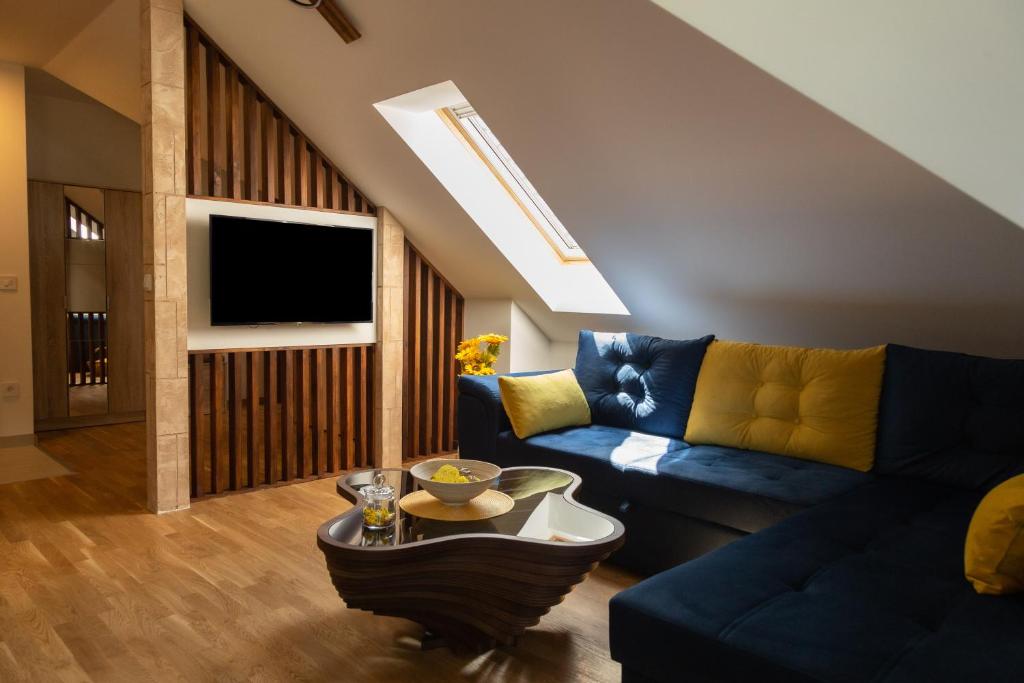 Zlatibor Apartman & Spa Casa Perfetta في زلاتيبور: غرفة معيشة مع أريكة زرقاء وتلفزيون